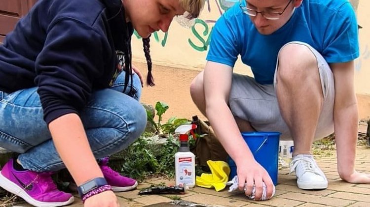 zwei Mitglieder unseres Jugendarbeitskreises putzen die Stolpersteine in Schwerin
